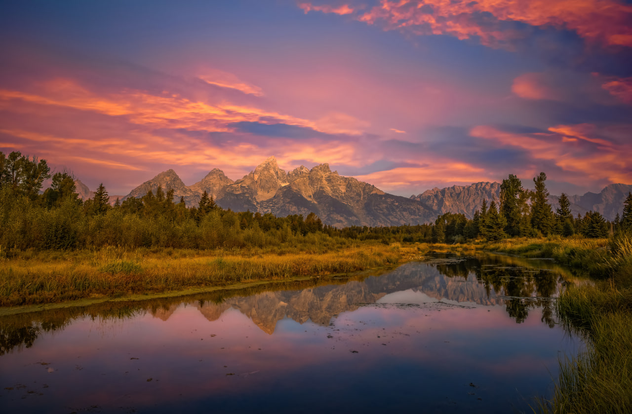 Morning light over the Teton Range at Schwabacher Landing reflected in calm water.