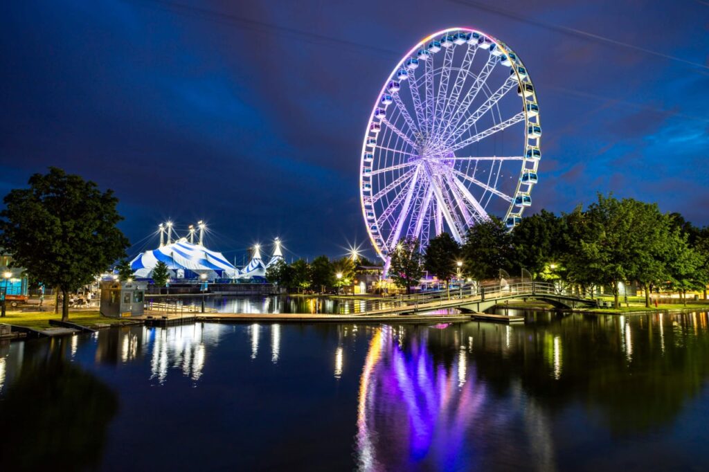Montreal Old Port observation wheel illuminated at night with reflections on the water