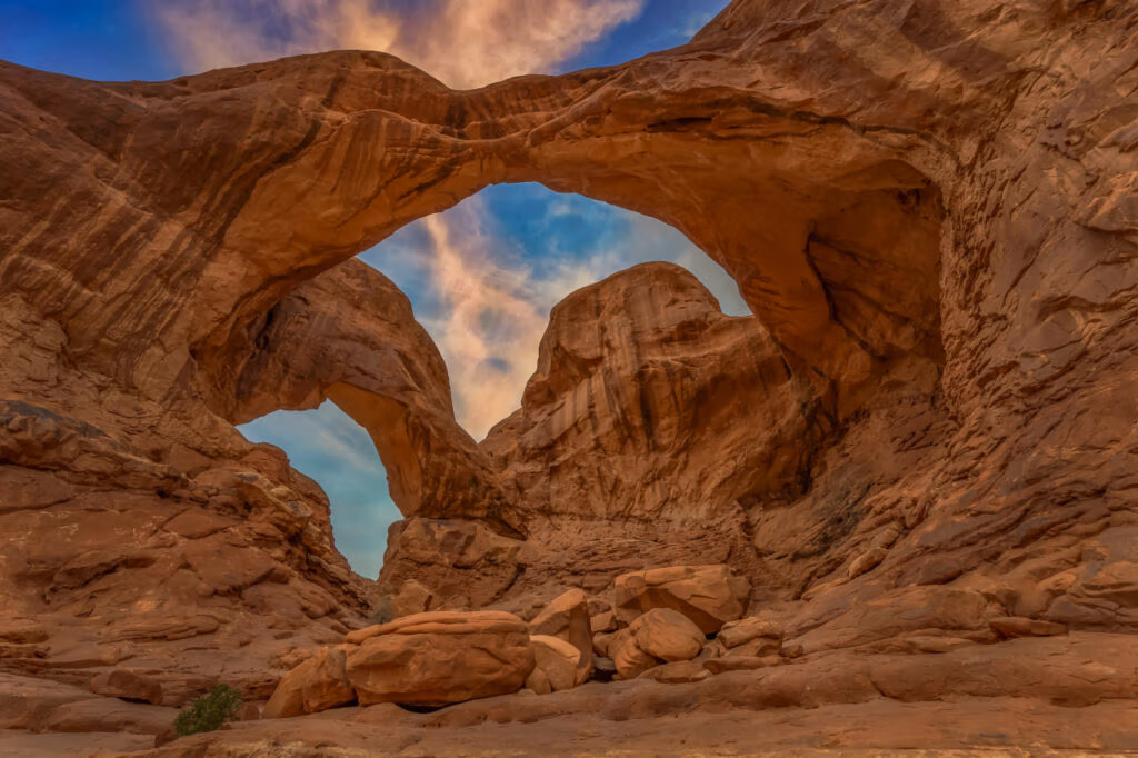 Double Arch in Arches National Park, Utah, beneath a blue sky with warm evening clouds