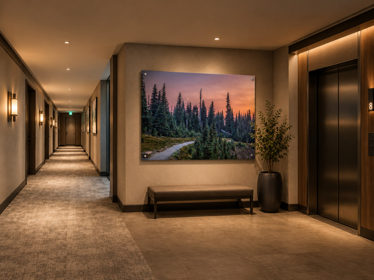 Warm hotel elevator lobby with a large twilight forest landscape photograph above a bench, beside dark elevator doors.