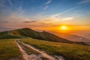 Winding mountain road across green hills at sunset at Bek-Kongoy Panorama near Bishkek, Kyrgyzstan
